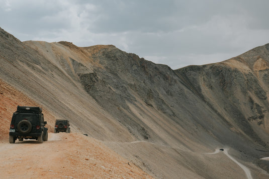 Jeeps in tandem on dirt road cut into barren hillside. Photo by Brady Stoeltzing.