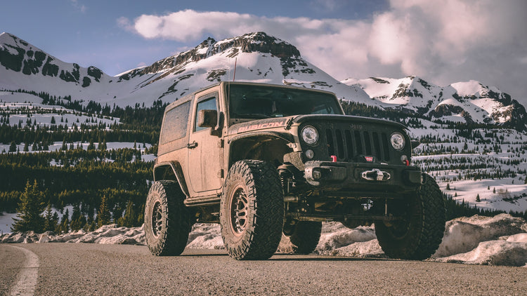 Jeep covered in mud in front of sow covered mountains. Photo by Cody Lannom.