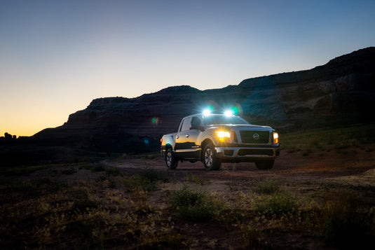 Truck at dusk with lights on, hills beyond. Photo by Mike Newbry