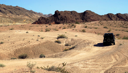 Black Jeep on dirt road in desert valley. Photo by Nicolas Cool.