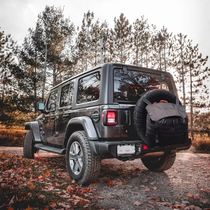Rear tire bag installed on grey jeep in woodland