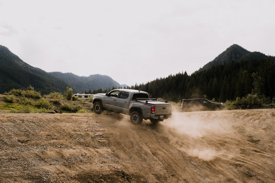 Truck on inclined dirt hill. Mountains beyond. Photo by Blake Carpent