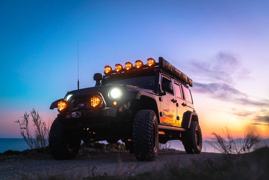Jeep at dusk with off road lights turned on. Sunset in back ground.
